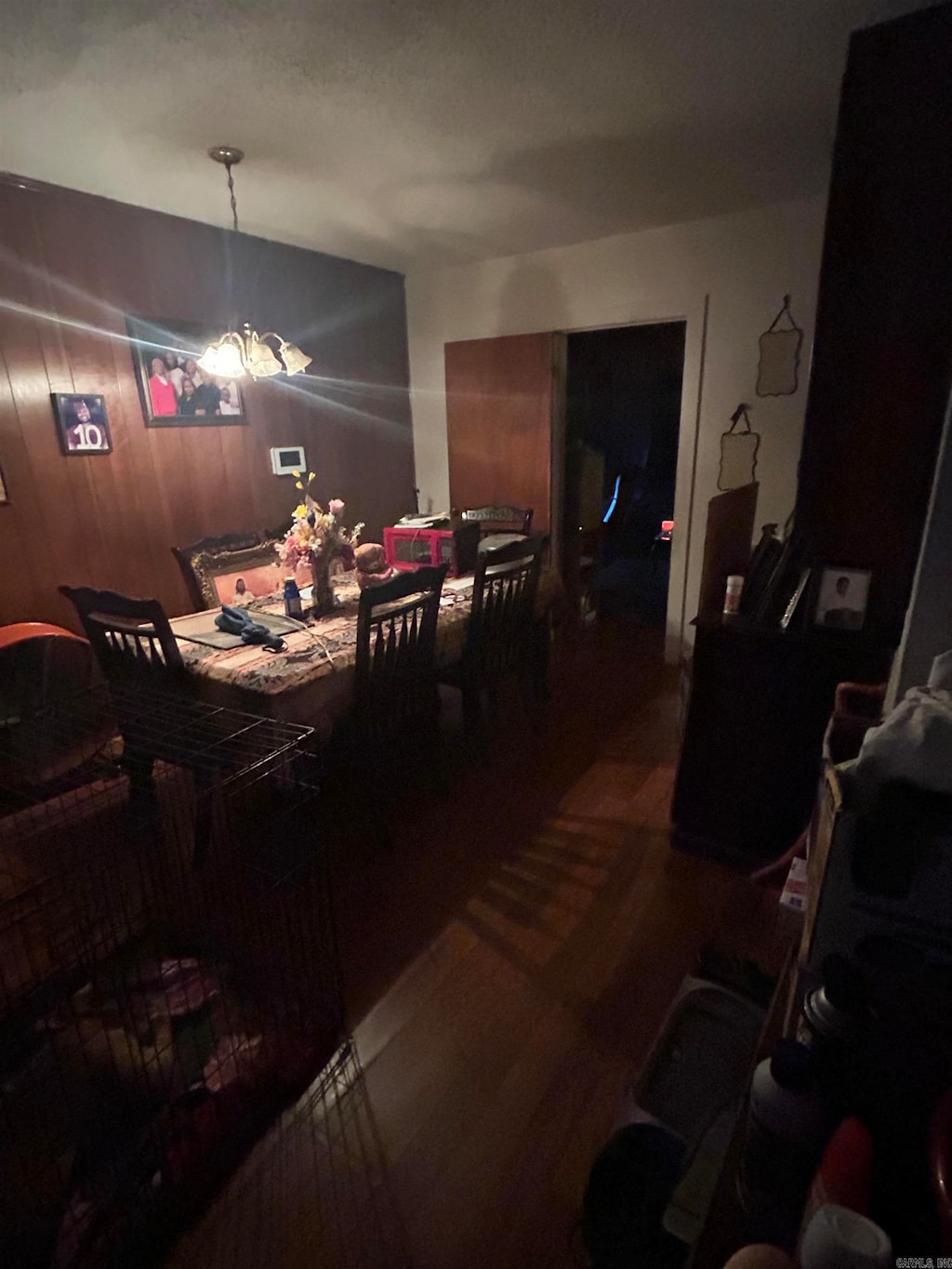 dining space with wooden walls, wood-type flooring, and a notable chandelier