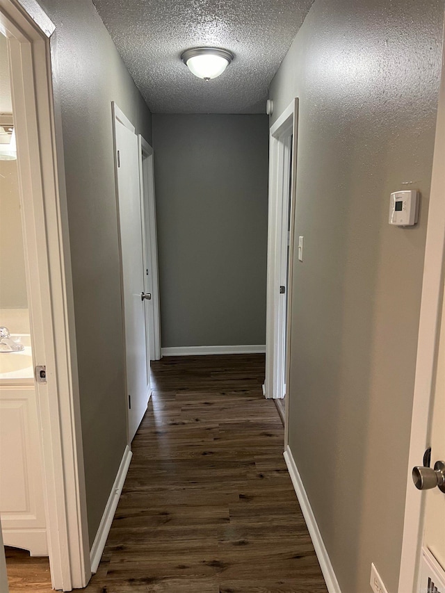 corridor with dark wood-type flooring and a textured ceiling