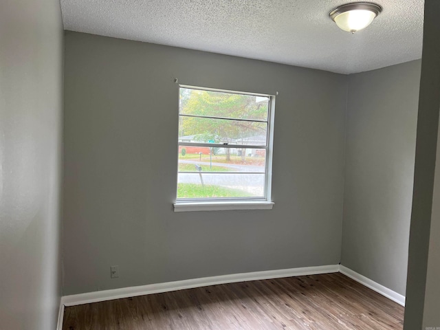 empty room with hardwood / wood-style floors and a textured ceiling