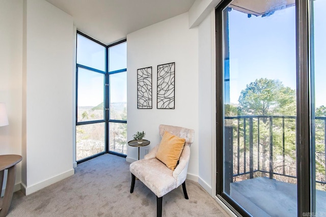 living area with plenty of natural light, light carpet, and floor to ceiling windows