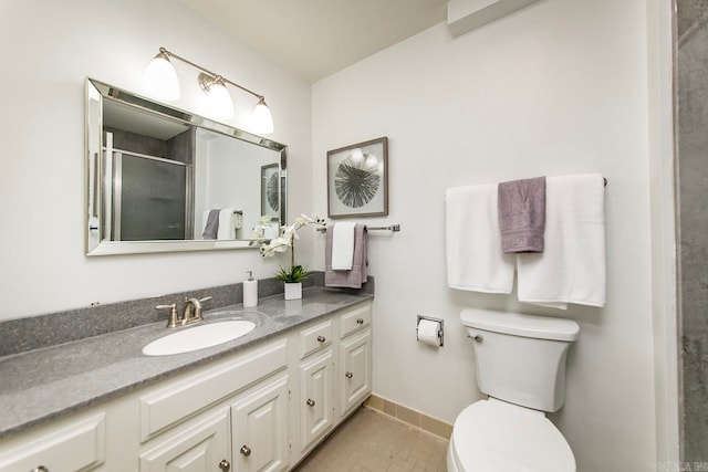 full bath with vanity, a shower stall, toilet, and baseboards