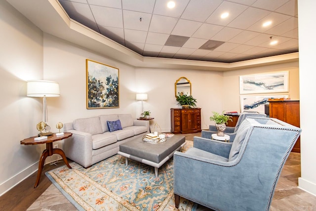 living area with baseboards and a raised ceiling