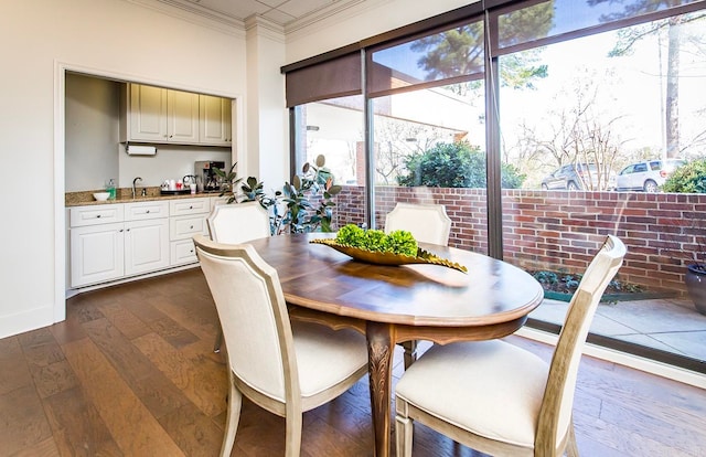 dining space with dark wood-style floors, ornamental molding, and baseboards