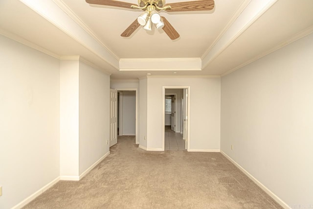 carpeted empty room featuring ceiling fan, ornamental molding, and a raised ceiling