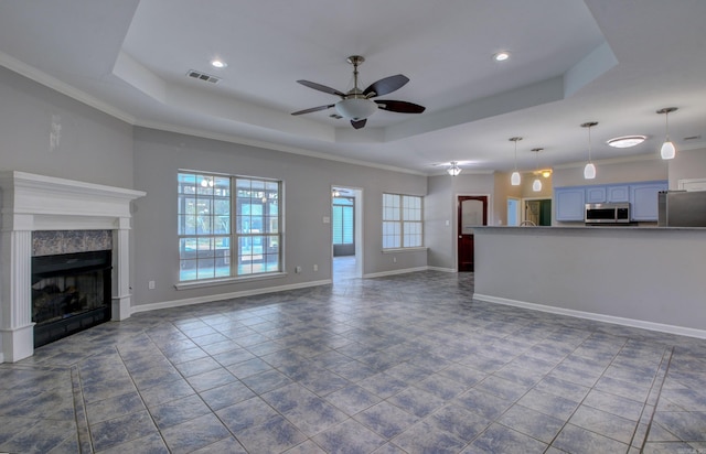 unfurnished living room with ornamental molding, a premium fireplace, and a raised ceiling