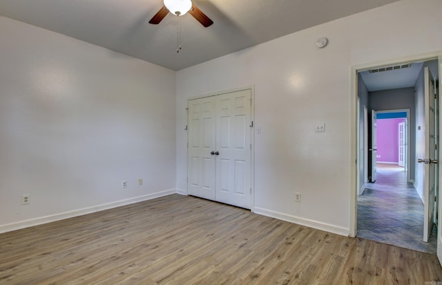 unfurnished bedroom with light hardwood / wood-style floors, ceiling fan, and a closet