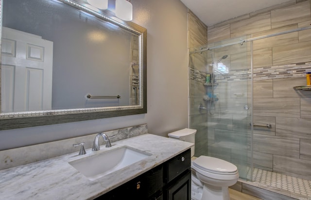 bathroom featuring toilet, vanity, and a shower with shower door