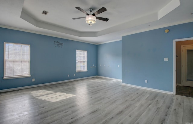 unfurnished room with light hardwood / wood-style floors, crown molding, and a tray ceiling