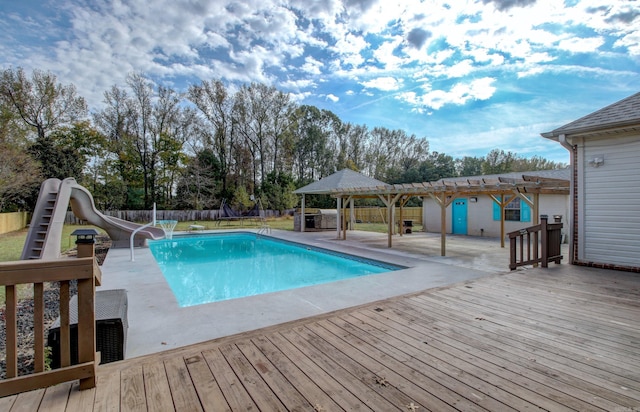 view of pool with a wooden deck, a patio, a pergola, and a water slide