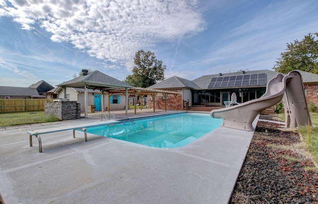 view of pool featuring a water slide, a diving board, and a patio area