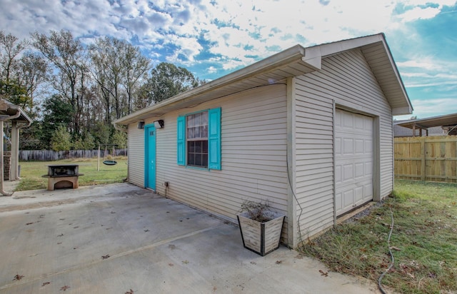 view of side of home with a garage, an outdoor structure, a patio, and a yard