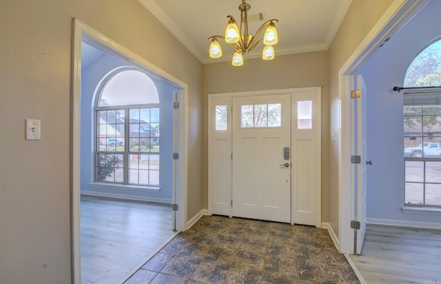 foyer entrance featuring ornamental molding, dark hardwood / wood-style flooring, a notable chandelier, and a healthy amount of sunlight