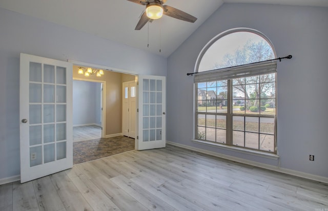 empty room with french doors, ceiling fan, light wood-type flooring, and vaulted ceiling