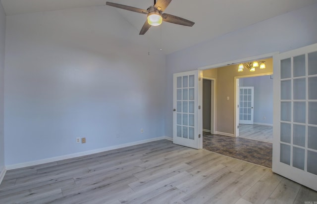 empty room featuring light hardwood / wood-style floors, ceiling fan, vaulted ceiling, and french doors