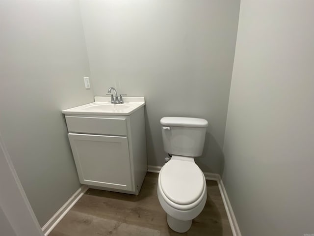 bathroom featuring toilet, vanity, and hardwood / wood-style flooring