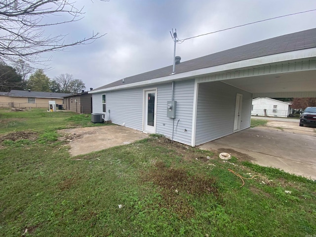 rear view of property featuring a yard, a carport, and central AC