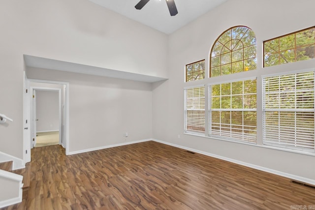 empty room featuring dark hardwood / wood-style flooring, high vaulted ceiling, and ceiling fan