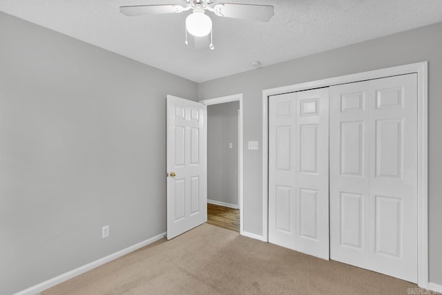 unfurnished bedroom featuring a textured ceiling, light carpet, ceiling fan, and a closet