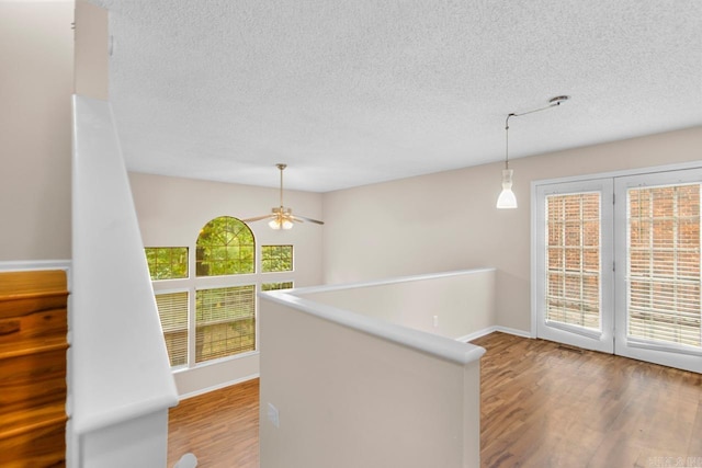 26 Summerwood Cv, Benton, AR 72015 - hallway featuring wood finished floors, baseboards, a textured ceiling, and an upstairs landing