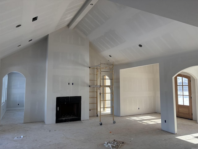 unfurnished living room featuring beam ceiling and high vaulted ceiling