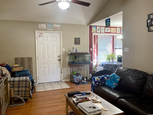 living room with ceiling fan, lofted ceiling, wood-type flooring, and a textured ceiling