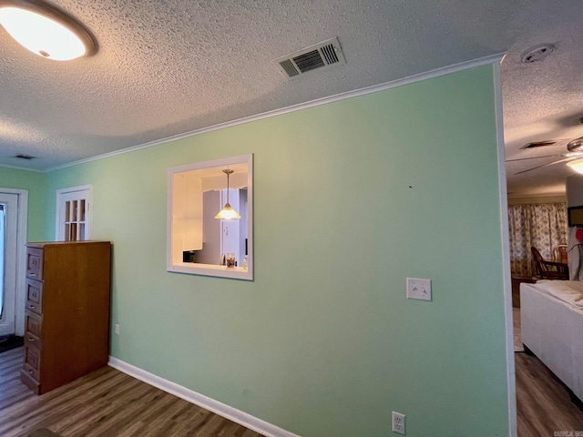 unfurnished bedroom with a textured ceiling, wood finished floors, crown molding, and baseboards