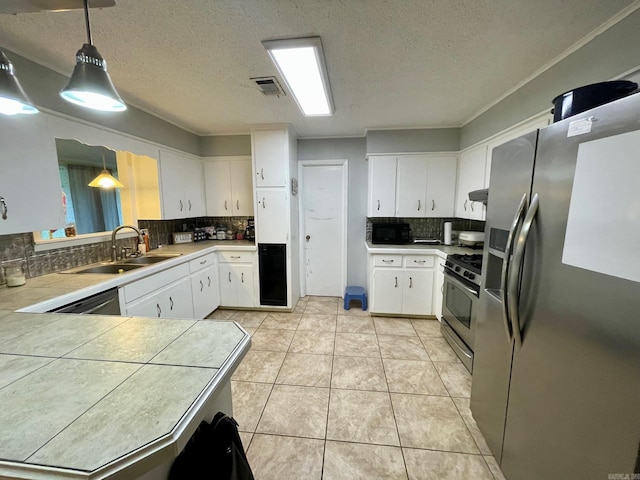 kitchen featuring stainless steel appliances, a sink, tasteful backsplash, a textured ceiling, and white cabinets