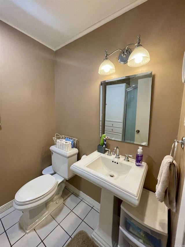 bathroom with tile patterned floors, toilet, ornamental molding, baseboards, and a shower with door