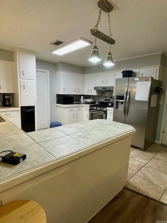 kitchen with appliances with stainless steel finishes, white cabinets, a textured ceiling, pendant lighting, and under cabinet range hood