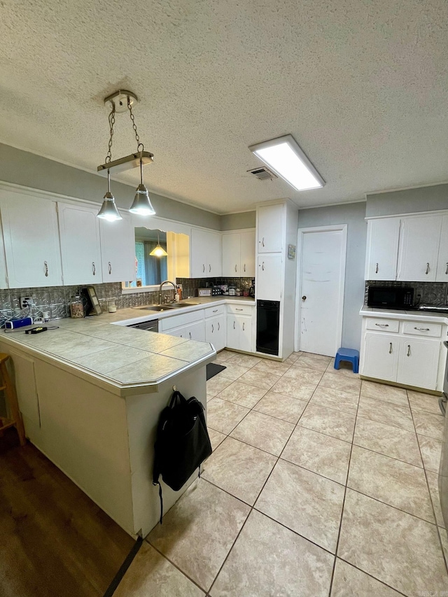 kitchen featuring a sink, backsplash, white cabinets, a peninsula, and a textured ceiling