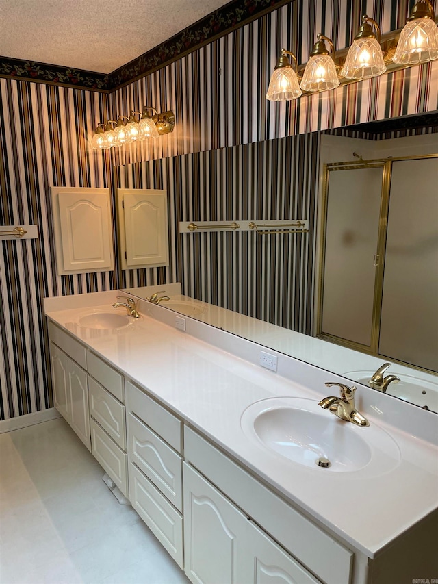 bathroom with vanity, a shower with door, and a textured ceiling