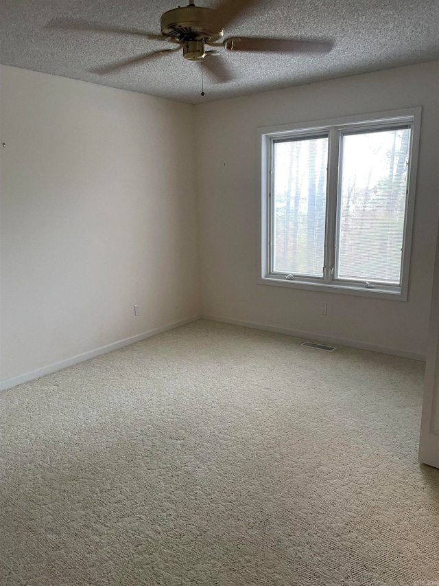 empty room featuring a textured ceiling, carpet flooring, and ceiling fan