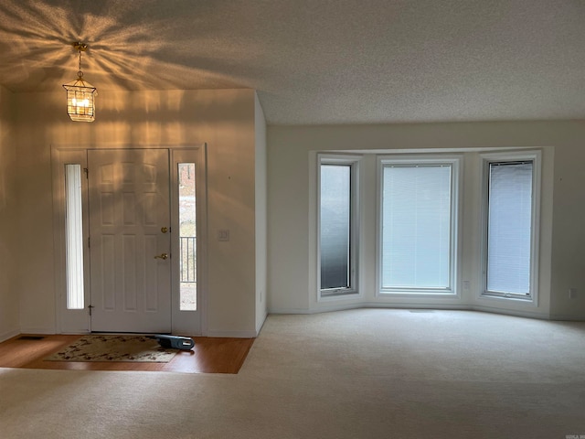 carpeted foyer with a textured ceiling and a chandelier