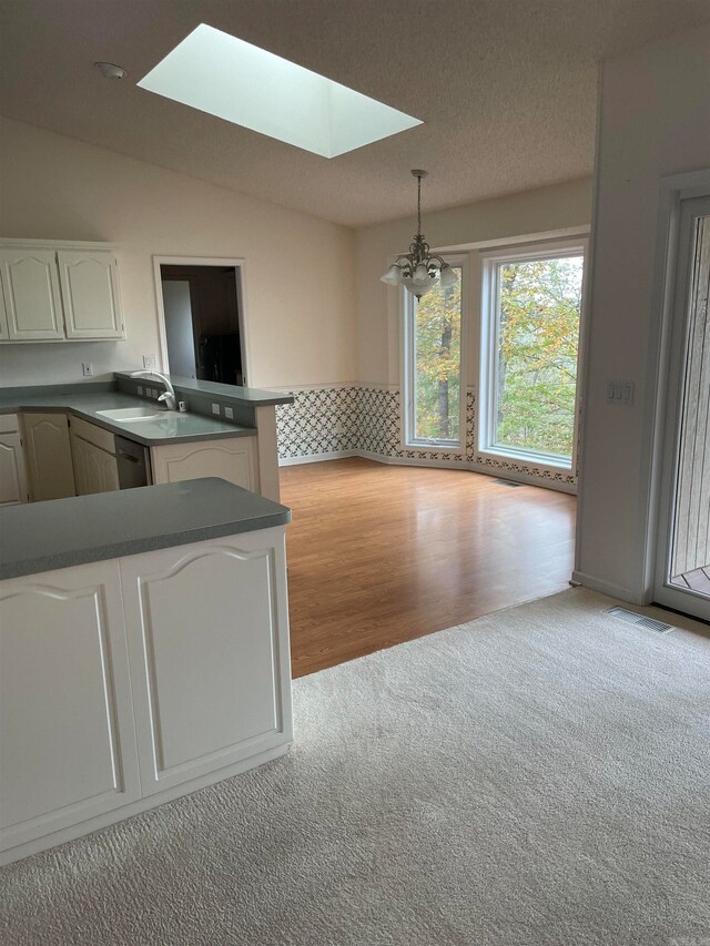 interior space featuring light hardwood / wood-style floors, an inviting chandelier, a textured ceiling, sink, and lofted ceiling with skylight