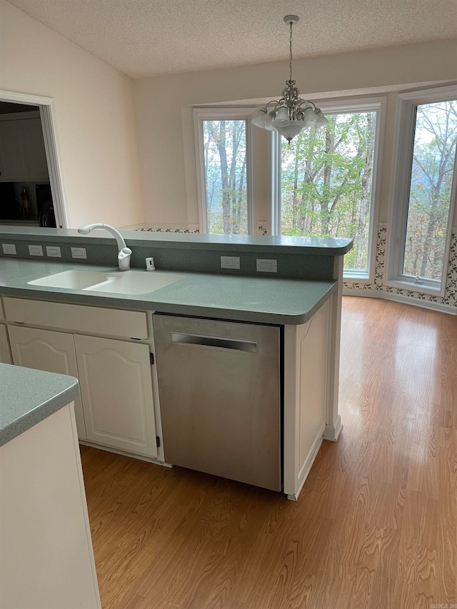 kitchen with a healthy amount of sunlight, white cabinets, dishwasher, hanging light fixtures, and light hardwood / wood-style flooring