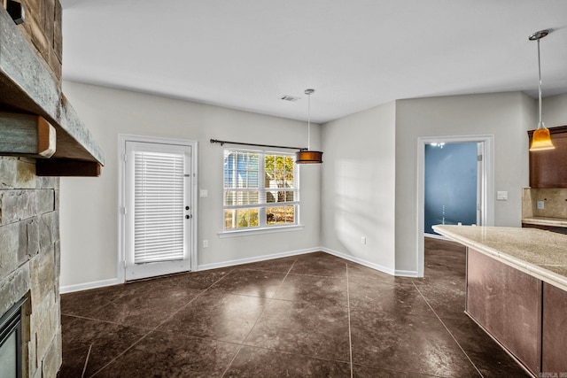 unfurnished dining area with a fireplace and dark tile patterned flooring