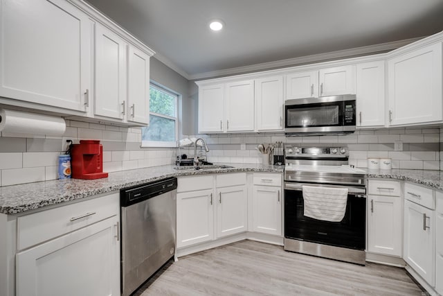 kitchen with sink, backsplash, white cabinets, and appliances with stainless steel finishes