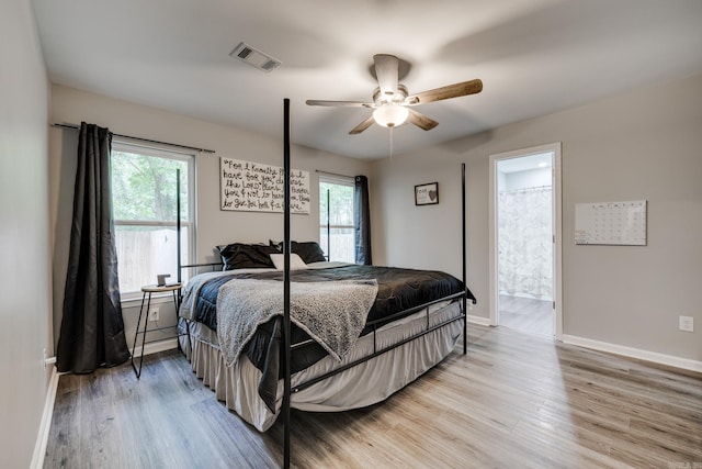 bedroom with ceiling fan, ensuite bath, and light hardwood / wood-style flooring