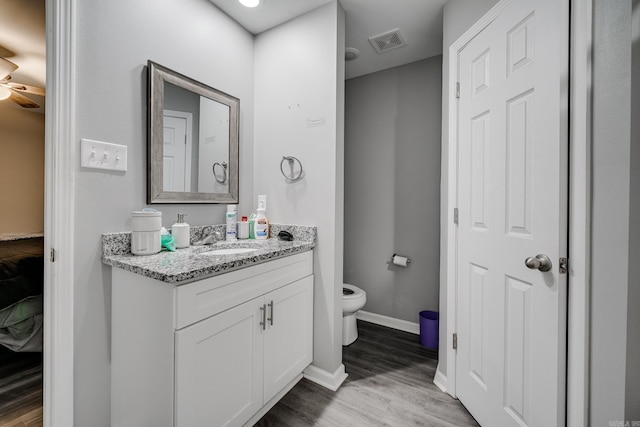 bathroom featuring vanity, ceiling fan, hardwood / wood-style flooring, and toilet