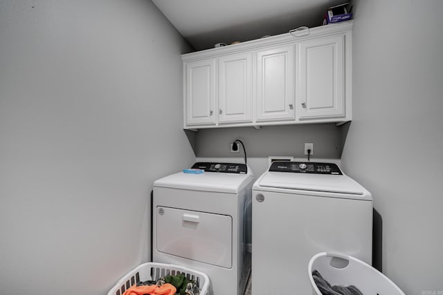 clothes washing area with washer and dryer and cabinets