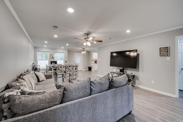 living room featuring hardwood / wood-style flooring, ornamental molding, and ceiling fan