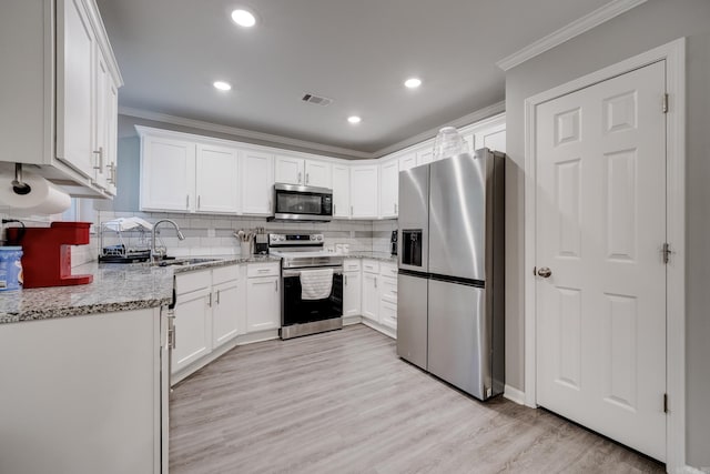 kitchen featuring stainless steel appliances, light stone countertops, sink, and white cabinets