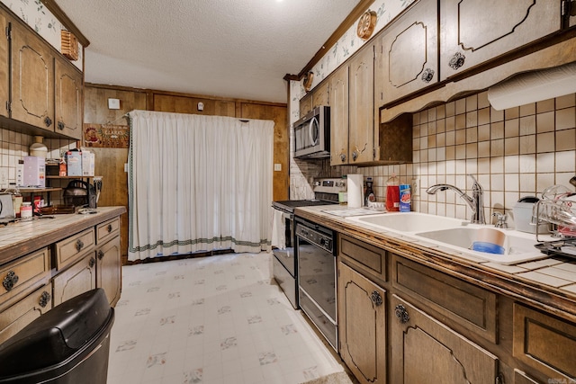 kitchen with tile counters, stainless steel appliances, a textured ceiling, and sink