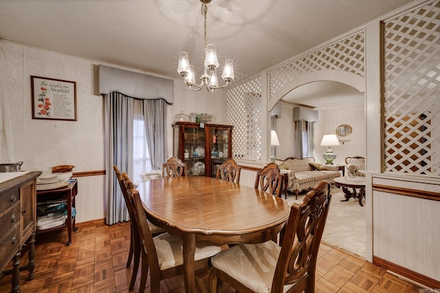 dining area featuring ornamental molding, a textured ceiling, a notable chandelier, and parquet floors