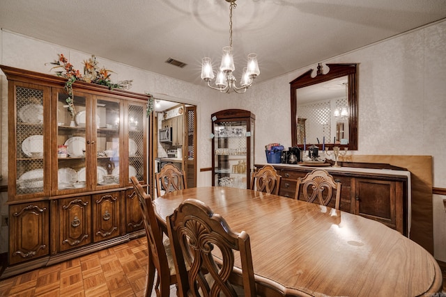 dining room featuring light parquet flooring, a textured ceiling, and a notable chandelier