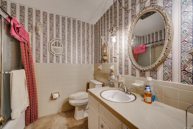 bathroom with vanity, toilet, and tile walls