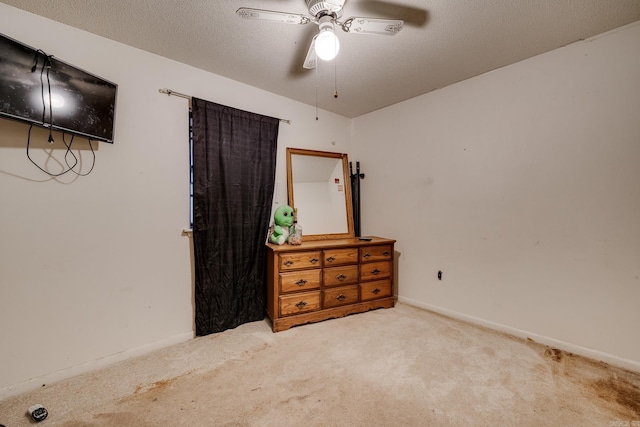 carpeted bedroom with ceiling fan and a textured ceiling