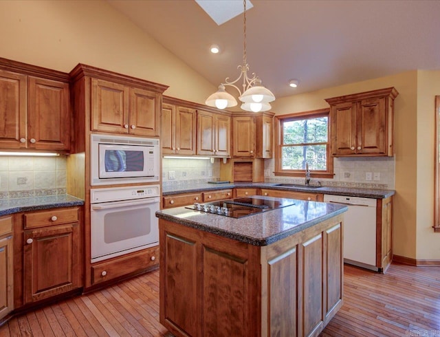 kitchen with white appliances, tasteful backsplash, vaulted ceiling, and a center island