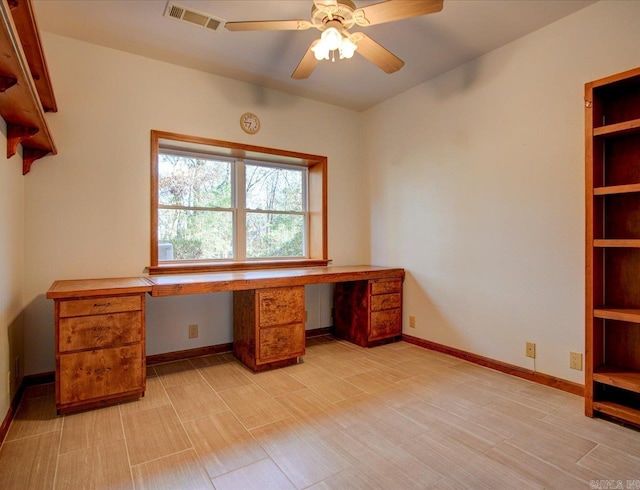 unfurnished office with built in desk and ceiling fan