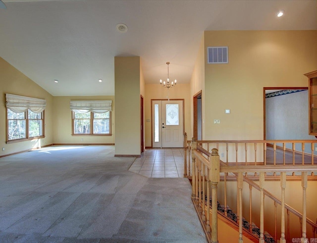 foyer entrance with high vaulted ceiling, light carpet, and a notable chandelier